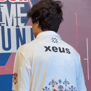 a man wearing a white shirt with the word xeus on it