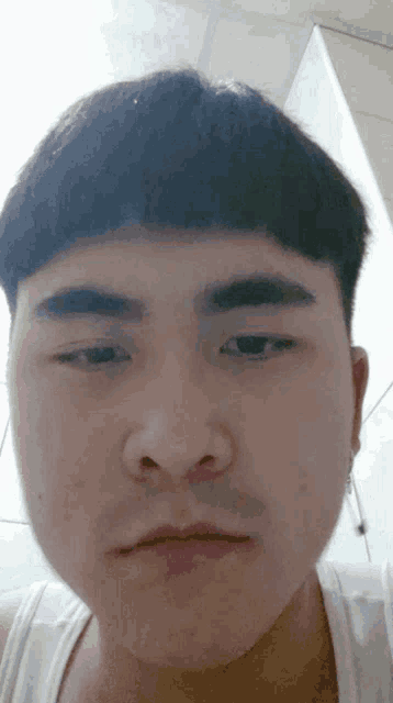 a close up of a person 's face with a white tank top on