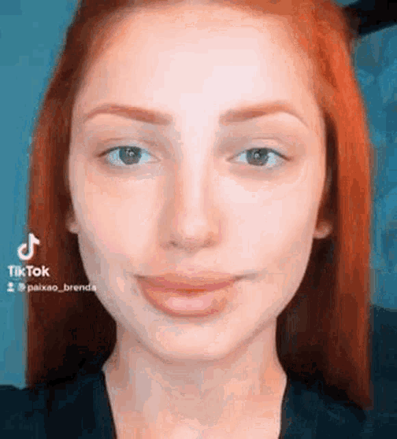 a close up of a woman 's face with red hair and a black shirt .