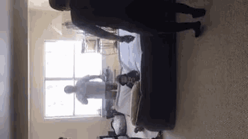 a group of people are standing in a room next to a bed .