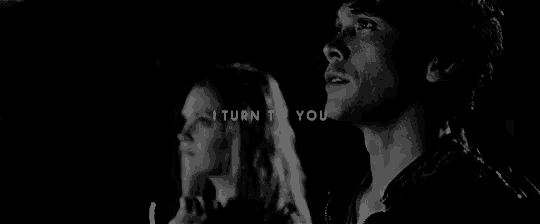 a black and white photo of a man and a woman standing next to each other in the dark .