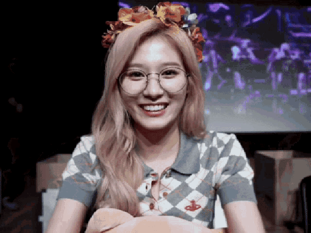 a woman wearing glasses and a flower headband is smiling .