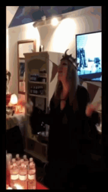 a woman with a crown on her head is screaming in front of a tv