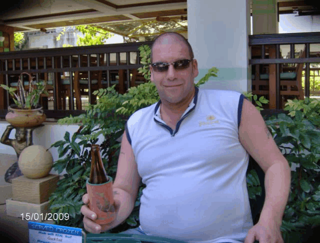 a man is holding a bottle of beer in front of a sign that says frozen drinks
