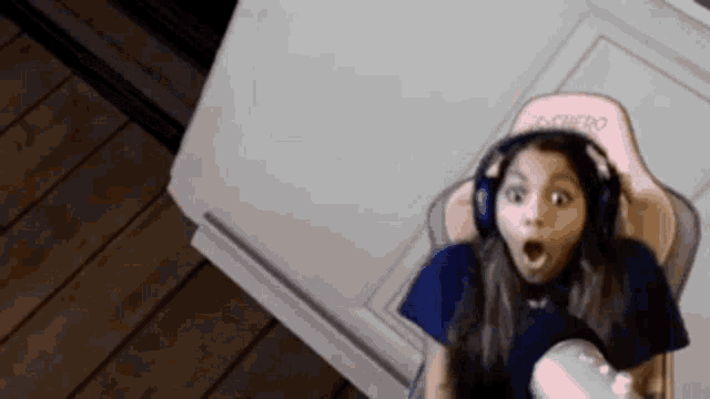 a little girl is wearing headphones and sitting in a chair .
