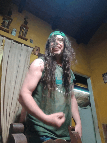 a man with long curly hair wearing a green shirt that says ' moran ' on it