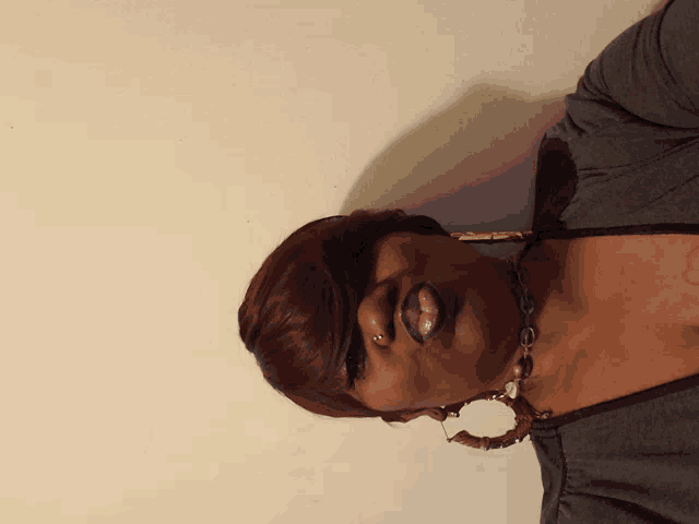 a woman wearing hoop earrings and a necklace with a tattoo on her chest