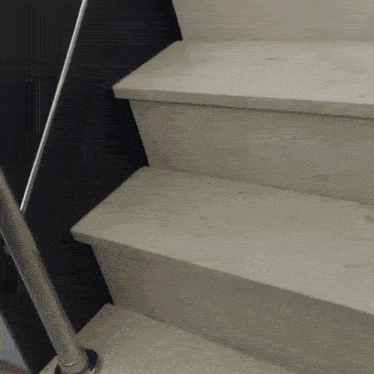 a set of stairs with a metal railing and a black wall behind them