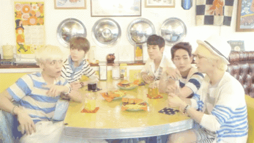 a group of young men sit at a diner table eating hamburgers