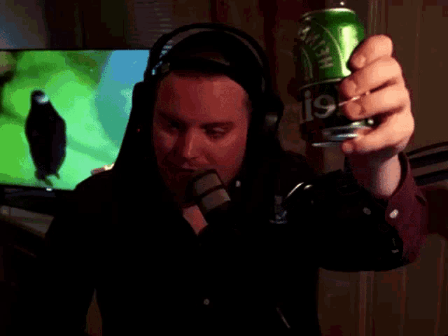 a man wearing headphones holds a can of heineken