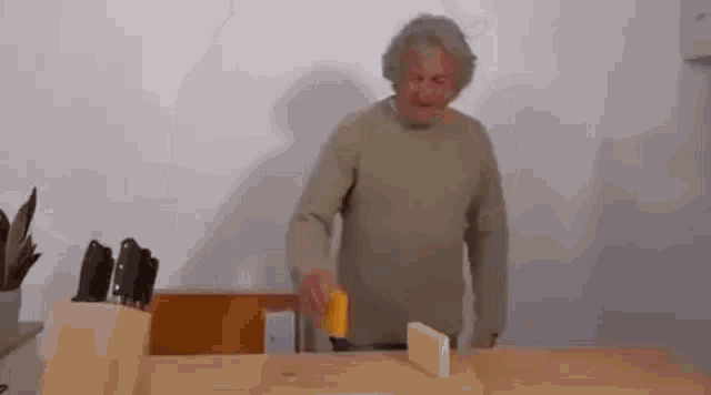 a man is cutting a piece of cheese on a wooden table .