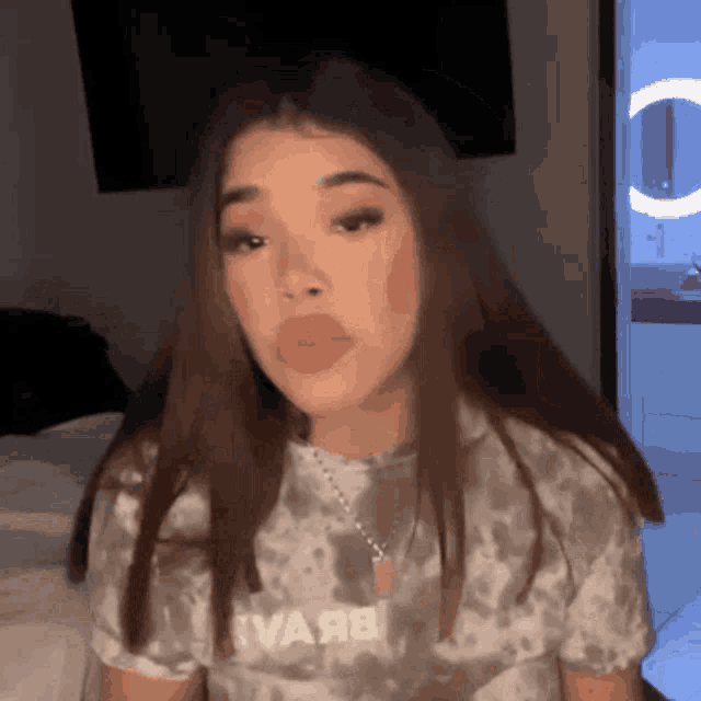 a girl is sitting on a bed wearing a tie dye shirt .