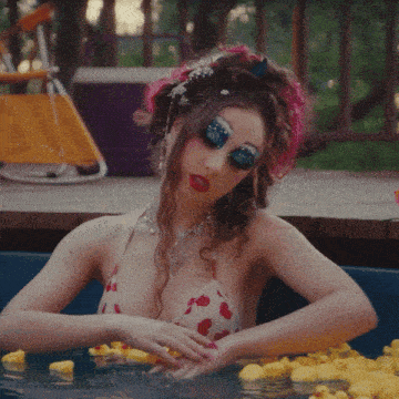 a woman in a bikini is sitting in a bathtub surrounded by rubber ducks