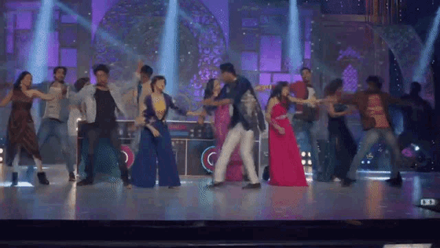 a group of people are dancing on a stage with purple lights