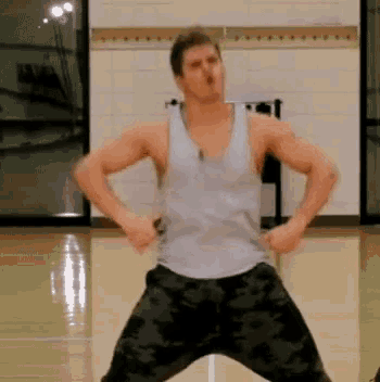a man in a tank top and camo pants is dancing