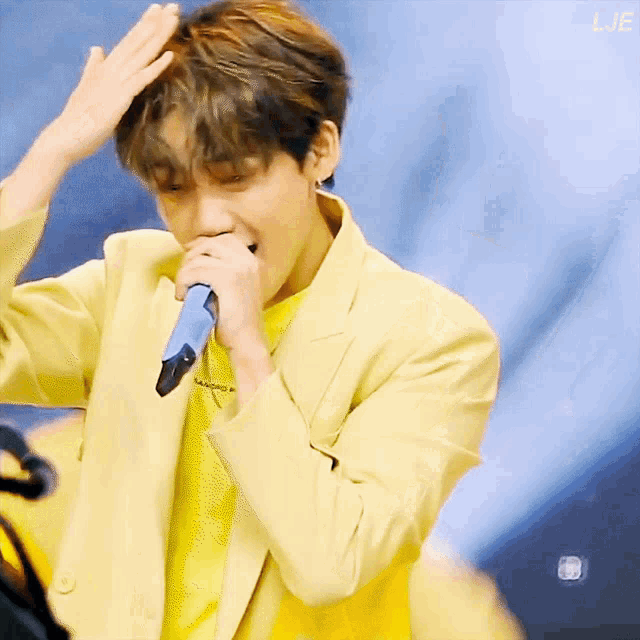 a man in a yellow jacket is singing into a microphone with the letters lje above him