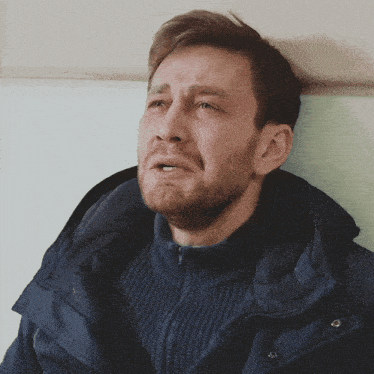 a man wearing a blue jacket is crying