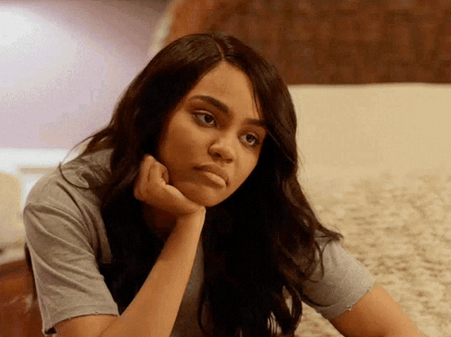 a woman with her hand on her chin is sitting on the floor