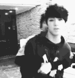 a black and white photo of a young man wearing a hoodie .