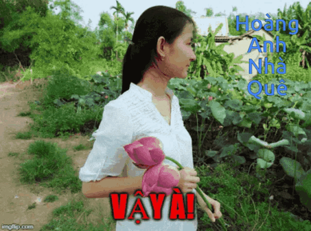 a woman in a white shirt is holding two pink flowers and says vava in red