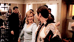 a man and a woman are dancing in a living room with other people .