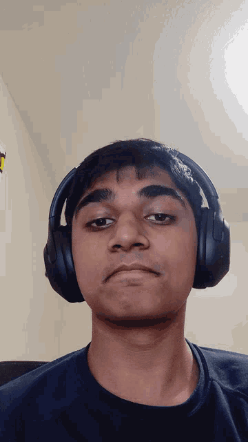 a man wearing headphones looks at the camera with a serious look on his face