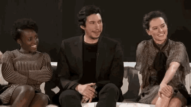 a group of people are sitting on a couch laughing together .