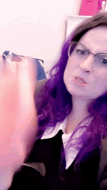 a woman with purple hair and glasses looks angry