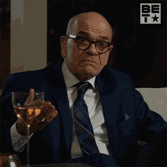 a man in a suit and tie holds a wine glass