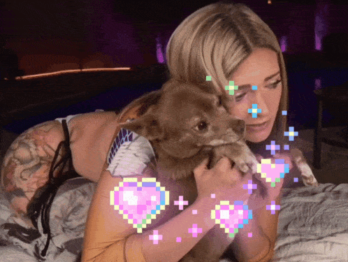 a woman laying on a bed holding a dog with pink hearts around her