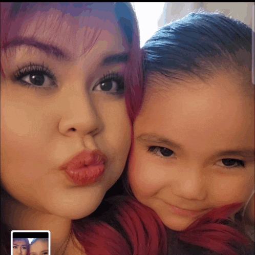 a woman with red hair and a little girl with black hair are posing for a picture
