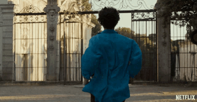 a man in a blue jacket is standing in front of a gate that says netflix