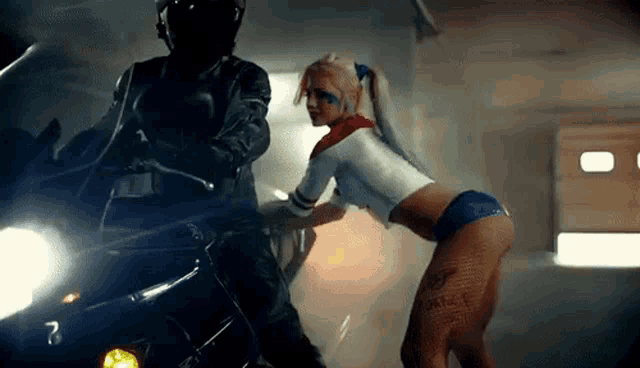 a woman in a harley quinn costume is standing next to a man on a motorcycle ..