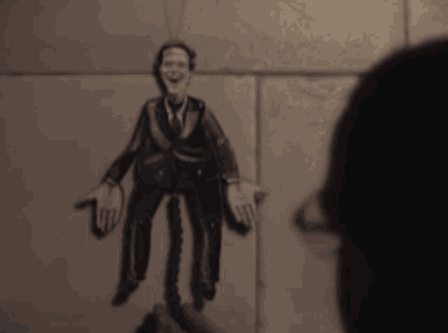 a puppet of a man in a suit and tie is being held by a person