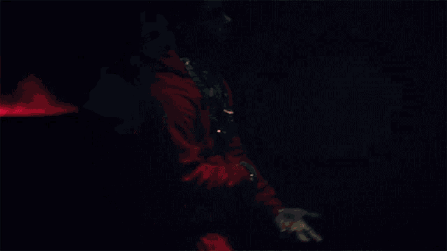 a man wearing a red hoodie and a necklace with the letter g on it