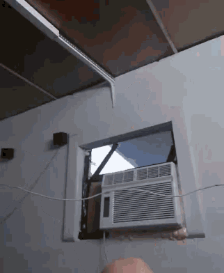 a white air conditioner is mounted to a white wall next to a window