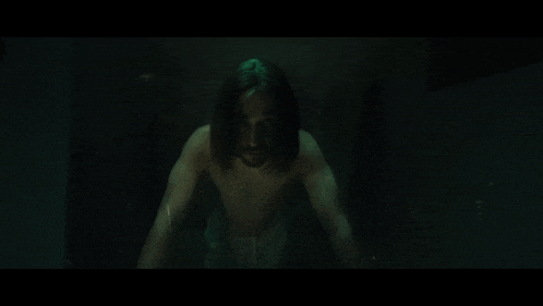 a man without a shirt is standing in the dark
