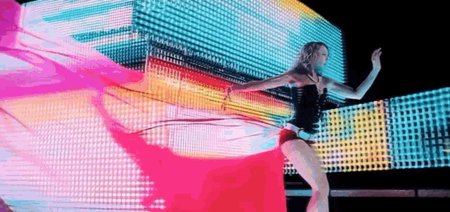 a woman is dancing in front of a giant screen .