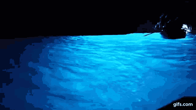 a boat is floating on top of a body of blue water in a cave .