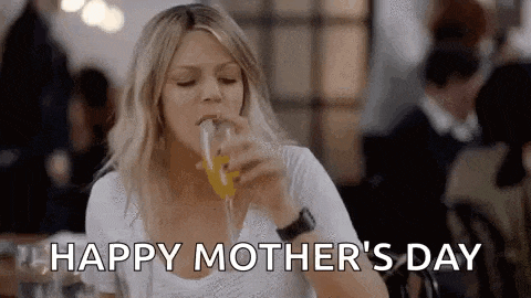 a woman is drinking a glass of orange juice in a restaurant and saying happy mother 's day .