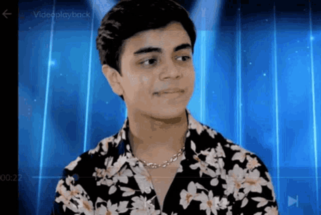 a young man is wearing a floral shirt and a video playback button is visible