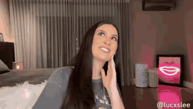 a woman with long hair is sitting in a living room with a pink light behind her .