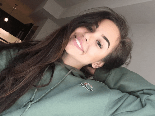 a woman wearing a green champion hoodie smiles