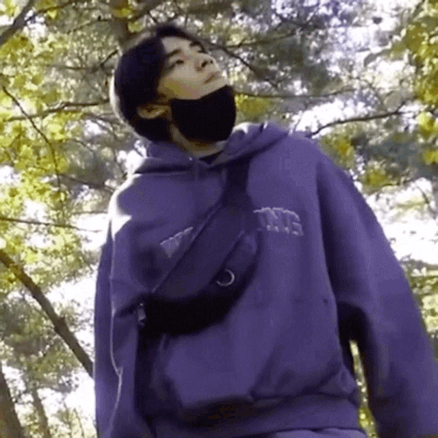 a man wearing a mask and a purple hoodie with the word converse on it