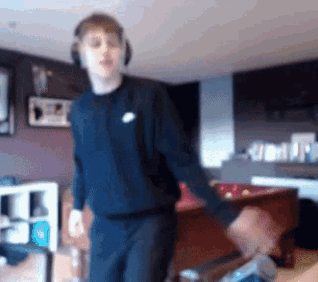 a man wearing headphones and a black nike shirt is standing in a living room