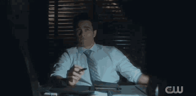 a man in a suit and tie is sitting at a desk with hilarious written on the screen behind him