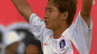 a soccer player wearing a white nike jersey is raising his arms