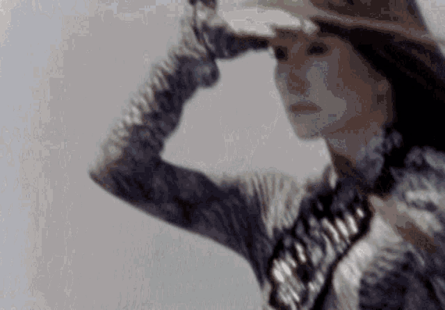 a woman wearing a hat and gloves is looking at something in the distance .
