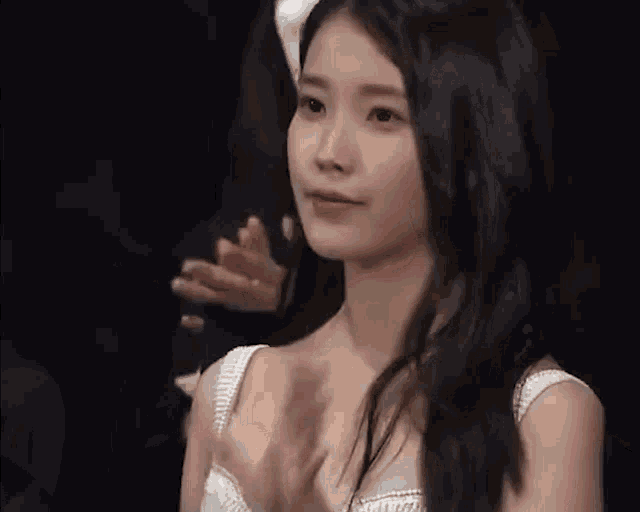 a woman in a white dress is clapping her hands while sitting in front of a crowd .