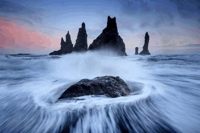 a group of rocks in the ocean with waves crashing on them
